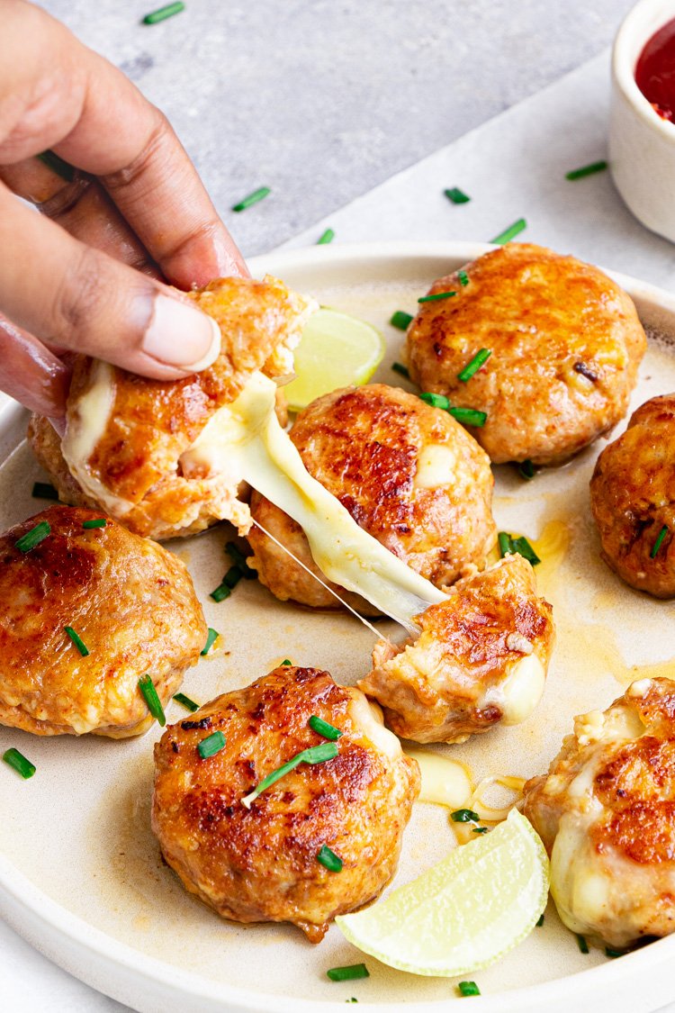 cheesy chicken fritters with cheese pulling, human hand is pulling the fritters