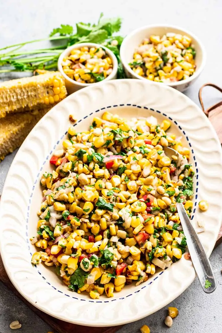 Roasted Corn Salad in a plate with cilantro, peanuts and tomato