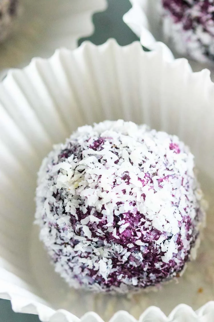 blueberry energy ball covered in shredded coconut, blueberry power ball